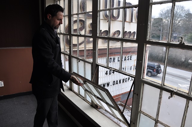 Fisher Paty, with Oakhurst Realty Partners, opens one of the windows of the projector room that's behind the Towne Cinema marquee. Photo by: Dan Whisenhunt