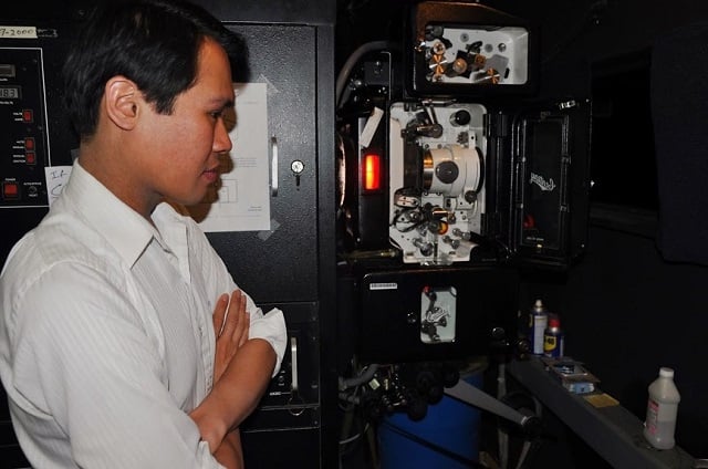 Marvin Evangelista looks inside the 35 mm projector in the Cinefest Film Theater at Georgia State University. Photo by: Dan Whisenhunt