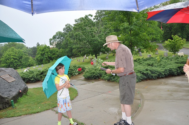 Chris Billingsley hands a rose to a little girl so she can place it on the veterans memorial at the Decatur Cemetery. Photo by Dan Whisenhunt