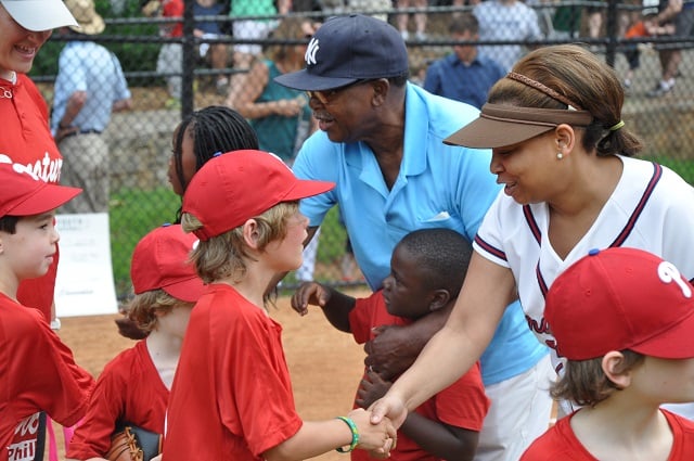 Marshall Kendrick, left, and Decatur City Commissioner Kecia Cunningham, right, shake hands with players in the city's summer youth baseball league. Photo by Dan Whisenhunt
