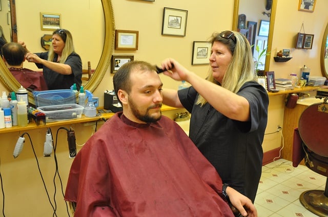Lisa Whiddon cuts the hair of longtime customer John Washburn at the Brass Chair Barbershop in Avondale Estates. Photo by Dan Whisenhunt