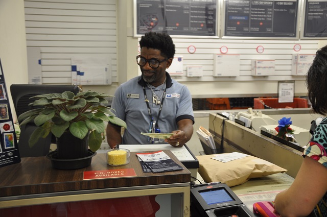 Leon Amos works behind the counter at the Avondale Estates Post Office on Aug. 15. Photo by Dan Whisenhunt