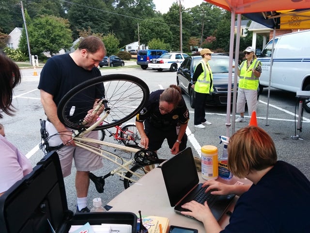Decatur Police Sgt. Dana Canape, center, looks for the bike's serial number so Police Sgt. Jennifer Ross, right, can record it in a computer. Photo by Dan Whisenhunt