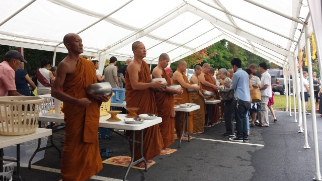 Theravada Buddhist monks stand at attention as lay supporters line up to give them alms. Photo by Dena Mellick
