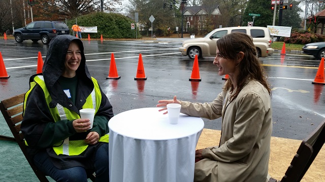 Stacy Reynolds (left) and Lisa Shaw, Avondale Estates residents and volunteers at Saturday's live demonstration, drink cider at a temporary table set up along U.S. Highway 278. Photo by Jill Nolin