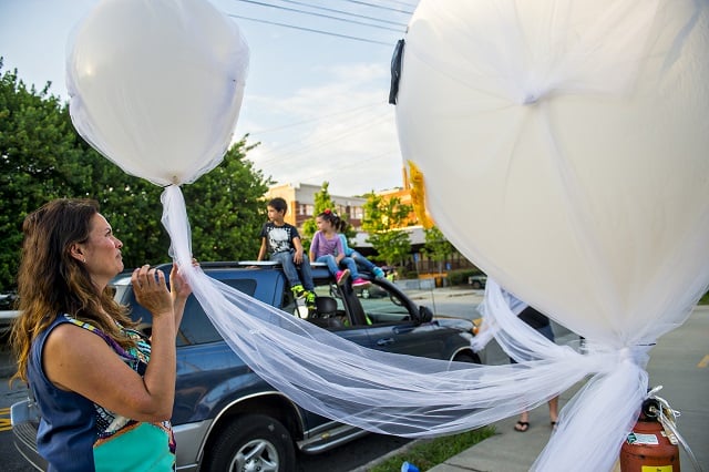 Daphne Cobb (left) ties helium balloons into her family's lantern before the start of the Decatur Lantern Parade. Photo: Jonathan Phillips