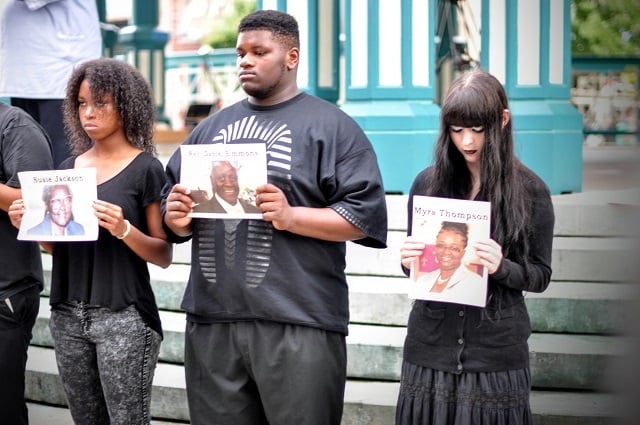 Volunteers hold pictures of the victims of a shooting in Charleston, S.C. Photo by Dan Whisenhunt