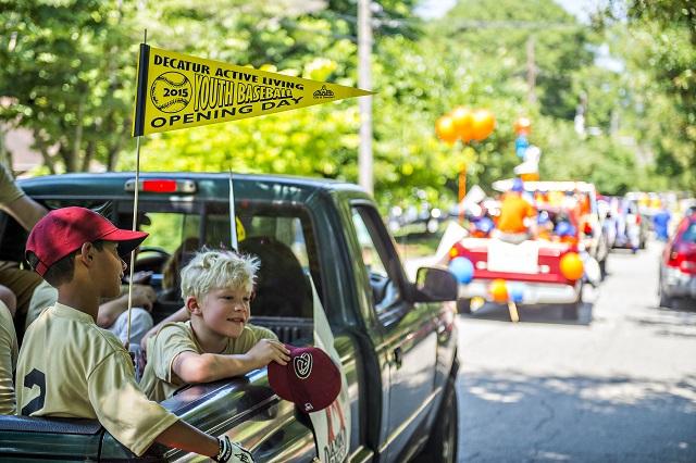 Teams with the Decatur Youth Baseball program ride in the back of trucks down East Lake Drive during a parade to celebrate opening day of the season on Saturday. Photo: Jonathan Phillips