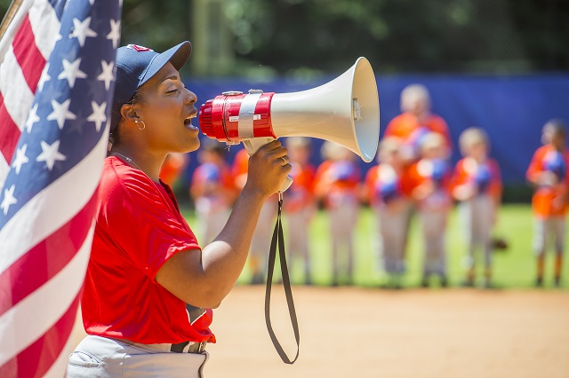 Artesha Chaney uses a bullhorn as she sings the national anthem during the ceremony for the opening day of Decatur Youth Baseball at Oakhurst Park. Photo: Jonathan Phillips