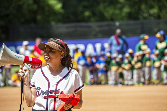 Keisha Cunningham (left) talks to teams using a bullhorn during the ceremony for the opening day of Decatur Youth Baseball at Oakhurst Park. Photo: Jonathan Phillips