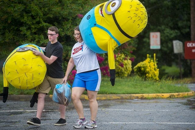 Brieson Cox (left) and Renee Davis carry minion costumes out of the rain before the start of the Avondale Estates 4th of July Parade on Saturday. Photo: Jonathan Phillips