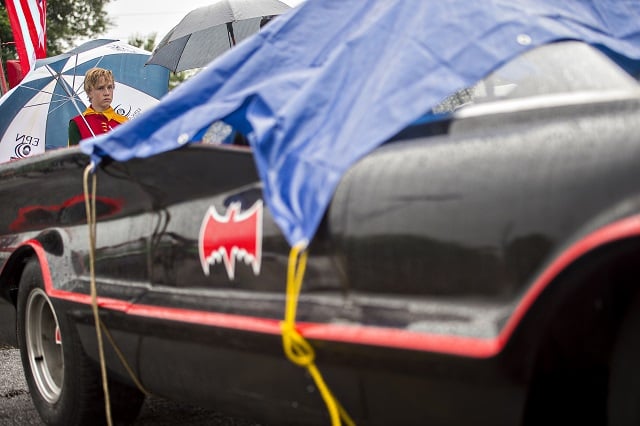 Dressed as Robin, J.J. Moran stands next to the Batmobile underneath an umbrella before the start of the Avondale Estates 4th of July Parade on Saturday.  Photo: Jonathan Phillips