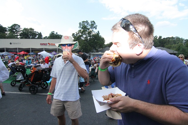 Brad Brickhouse takes a huge bite from a Fox Bros pulled pork BBQ sandwich. Photo by Travis Hudgons/Decaturish.com