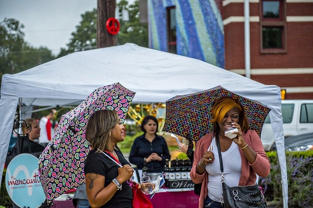 Billie Harris (left) and Dekeytra Walker protect themselves from the rain as they drink wine during the Kirkwood Wine Stroll on Friday. Photo: Jonathan Phillips