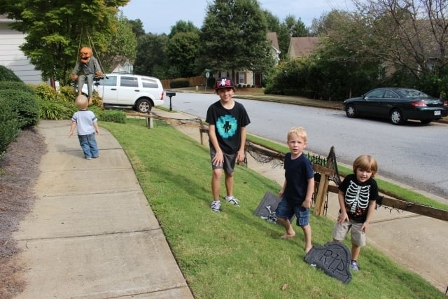 Neighbor Connor McKeown (2) looks intently at a decoration while Harrison O'Neal (9), Aidan McKeown (5), and Ronan O'Neal (4) check out the decorating work in progress. Jones-Mitchell says one tip she has for saving money is to buy Styrofoam tombstones and then split them in half. They look scarier and you get more for your money. Photo by Dena Mellick