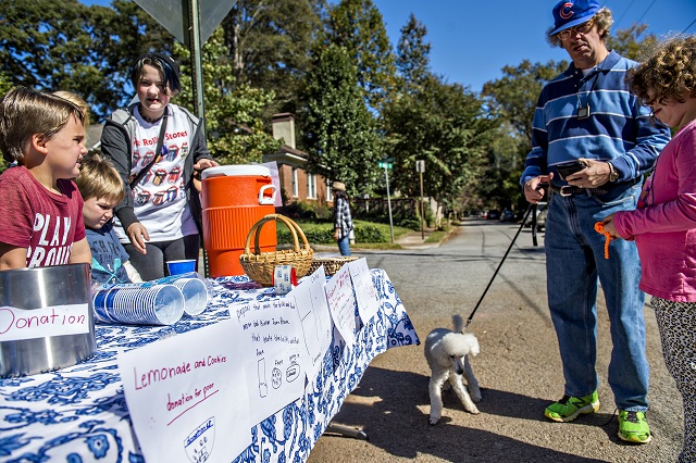 Maya Goren (right) and her father Bill get a glass of lemonade from Kat Butler and Kieran Dickmann as they raise money for a charity during the Oakhurst Porch Fest on Sunday. Photo: Jonathan Phillips
