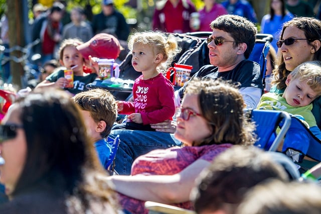 Mira Sonenblum (center) sits on her father Jason's lap as they listen to music during the Oakhurst Porch Fest on Sunday. Photo: Jonathan Phillips