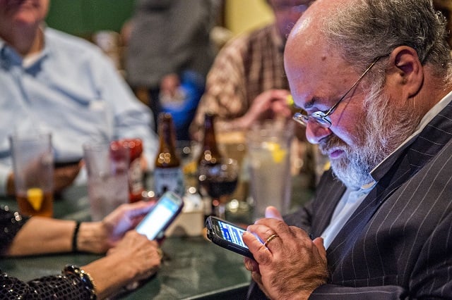 Dave Markus checks poll results on his phone during the Dekalb Strong viewing party at Melton's app & tap on Tuesday. Photo: Jonathan Phillips