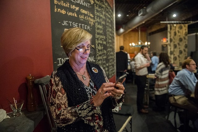 Mary Kay Woodworth checks polls results on her phone during the Lavista Hills viewing party at Sprig on Tuesday. Photo: Jonathan Phillips