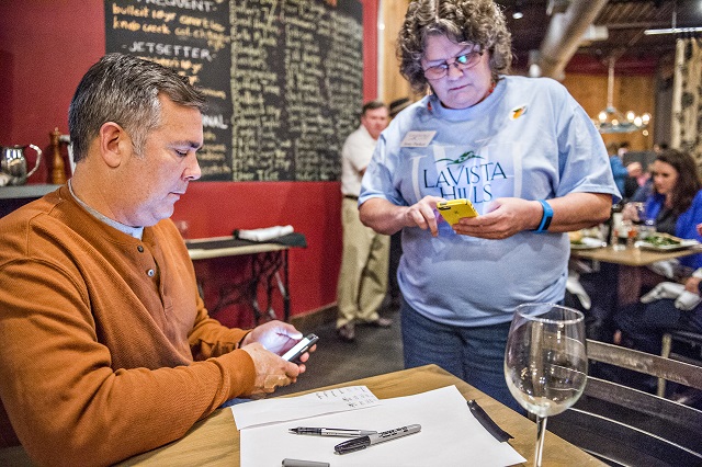 Matt Slappey (left) and Amy Parker check their phones for poll results during the Lavista Hills viewing party at Sprigs on Tuesday. Photo: Jonathan Phillips