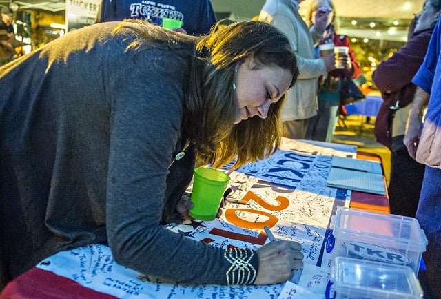 Sonja Szubski signs the Tucker 2015 sign during the election night party on Main St. on Tuesday. Photo: Jonathan Phillips