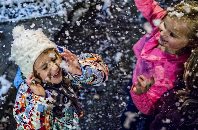 Emily Thompson (left) and Elizabeth Root play in fake snow as it falls in downtown Decatur during the annual lighting of the tree celebration on Thursday. Photo: Jonathan Phillips