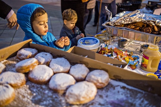 Benedict Lubell (left) and his brother Isaac move through the potato latke and jelly donut line during the Chanukah celebration in Decatur Square on Thursday. Photo: Jonathan Phillips