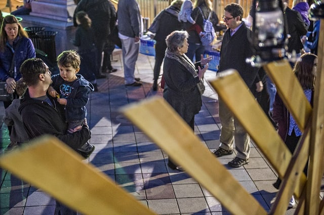 Matt Friedman (left) holds his son Jett in front of the giant menorah during the Chanukah celebration in Decatur Square on Thursday. Photo: Jonathan Phillips