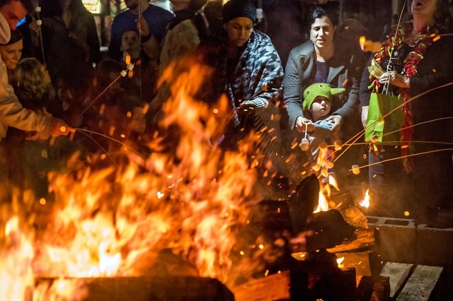 Lynne Gilespie (right) helps her son Quinn hold onto his stick during the annual marshmallow roast at Decatur Square on Thursday. Photo: Jonathan Phillips