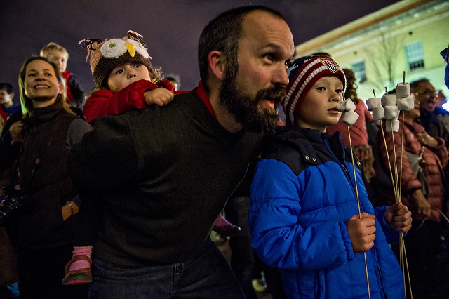 Addison Martinelli (left) holds onto her father Michael as he sing Christmas carols next to his son Aiden during the annual marshmallow roast at Decatur Square on Thursday. Photo: Jonathan Phillips