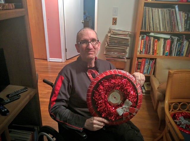 Greg Germani holds up a wreath made out of a vinyl record. Photo by Dan Whisenhunt