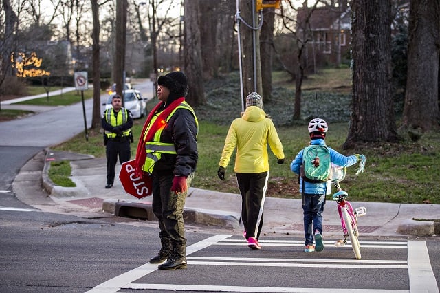 Theresa Stephens (left) stops traffic at the intersection of S. Candler St. and Kirk Rd. in Decatur so people can cross on their way to school during the Big Walk on South Candler event on Wednesday morning. Photo: Jonathan Phillips