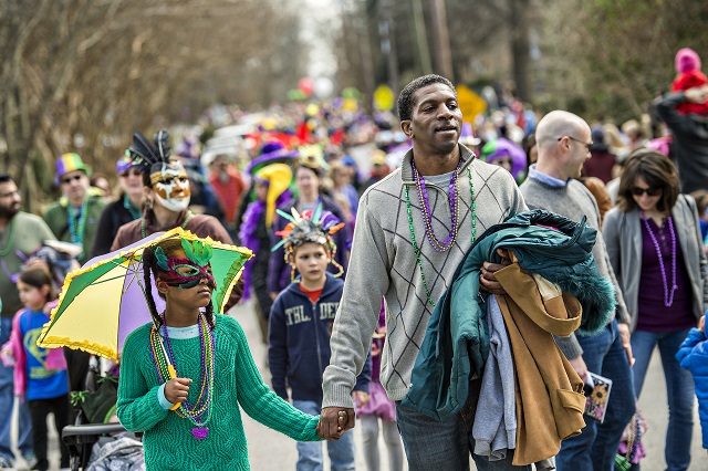 Milan Harris (left) holds her father Vincent's hand as they march down Mead Rd. during the Mead Rd. Mardi Gras Parade on Saturday. Photo: Jonathan Phillips