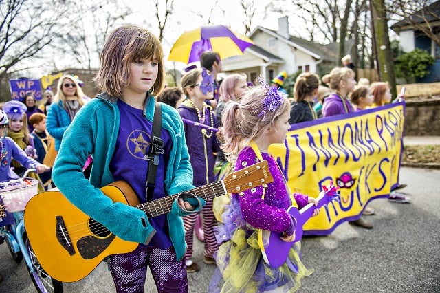 Sadie Hearsch (left) plays her guitar as she marches during the Mead Rd. Mardi Gras Parade on Saturday. Photo: Jonathan Phillips
