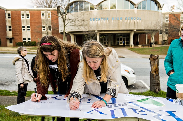Sarah Norman (left) and Sara Stubbs, the organizers of the Rally for Riley, write messages to Susan Riley on a sign as they set up for the event across from Decatur High School on Monday morning. Photo: Jonathan Phillips