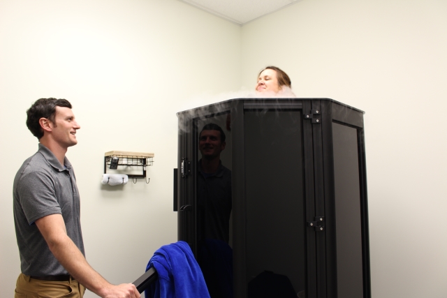 Dr. Danny Matta talks to Athletes' Potential Office Manager Claire Paskus as she demonstrates the cryotherapy machine. Photo by Dena Mellick