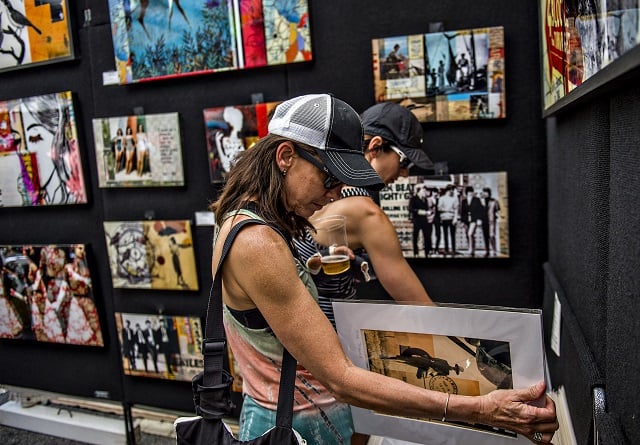 Angie Comer (left) and Stephanie Herbert look at Aaron Collier's artwork during the Decatur Arts Festival on Saturday. Photo: Jonathan Phillips