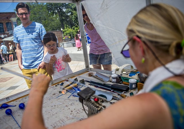 Kris Todd (left), Addison Harrell and her mother Emily watch as Joanne Paller blows glass during the Decatur Arts Festival on Saturday. Photo: Jonathan Phillips