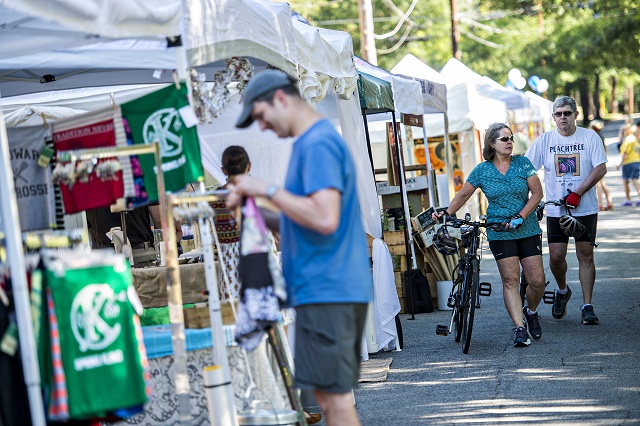 Carol Hostetter (center) and her husband Spencer walk their bikes past the artist booths during the Kirkwood Spring Fling on Saturday. Photo: Jonathan Phillips