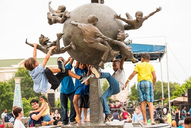 Children climb on the statue in the Decatur Square during the Decatur Beach Party.
