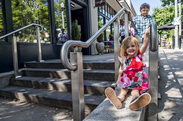 Josie Vance and Declan Llewellyn slide between the handrails as they wait to cross Church St. to get to the children's section of the Decatur Book Festival on Saturday. Photo: Jonathan Phillips