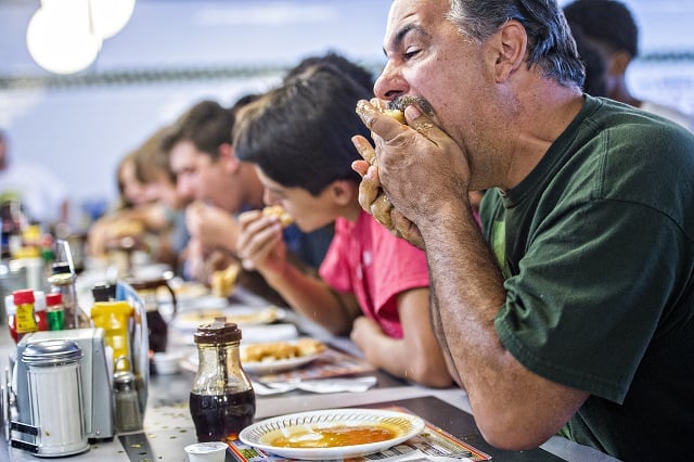 Steve Schultz (right) shoves a whole waffle into his mouth to gain an early lead during the waffle eating contest at the Waffle House in Decatur on Friday. Photo: Jonathan Phillips