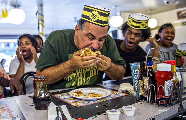 Steve Schultz (center) shoves a whole waffle into his mouth as he tries to make a move to take over the lead during the championship round of the waffle eating contest at the Waffle House in Decatur on Friday. Photo: Jonathan Phillips