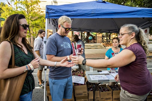 Alex Peister (right) hands out glasses and passports to Scott Jones and Sarah Fitzgerald during the Kirkwood Wine Stroll on Friday. Photo: Jonathan Phillips