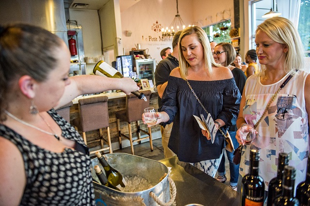 Laura Weatherford (right) and Elizabeth Campbell hold out their glasses as Savannah Kirkwood fills them with wine at Le Petite Manche during the annual Kirkwood Wine Stroll on Friday. Photo: Jonathan Phillips