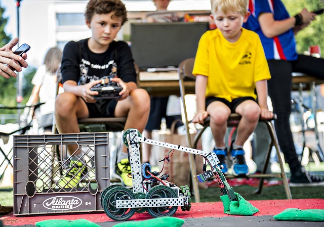 A robot under the control of Jackson Armstrong (left) picks up a beanbag as Owen Burke waits his turn during the Atlanta Maker Faire in Decatur on Saturday. Photo: Jonathan Phillips