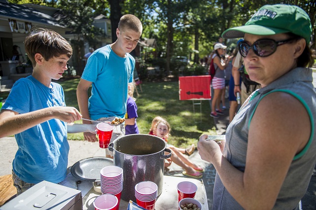 Sean Wiseman (left) and Connor Ramming scoop boiled peanuts into a cup for Lisa Chader during the annual Oakhurst Porchfest on Saturday. Photo: Jonathan Phillips