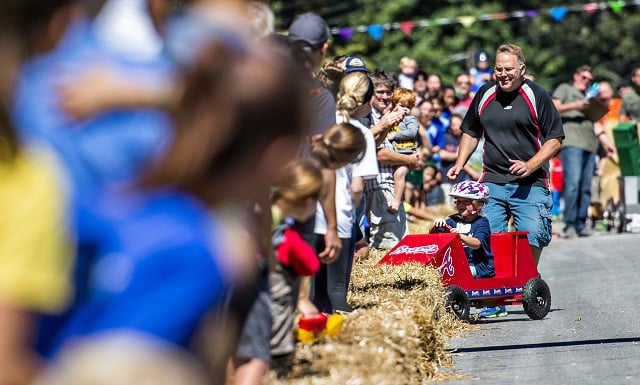 Chased by her father, Blythe Hart crashes into the hay bales during the 6th annual Madison Ave. Soapbox Derby in Oakhurst on Saturday. Photo: Jonathan Phillips