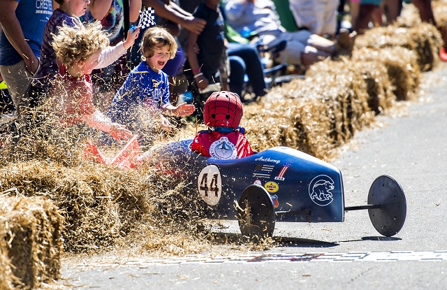 Anthony Amelio crashes into hay bales as he crosses the finish line during the 6th annual Madison Avenue Soapbox Derby on Saturday. Photo: Jonathan Phillips