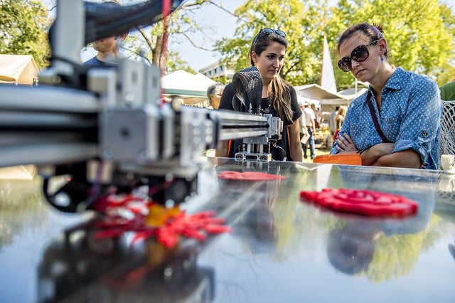 Alison Hight (right) and Emily Fitzharris watch as a 3D printer cuts a snowflake during the Atlanta Maker Faire in Decatur on Saturday. Photo: Jonathan Phillips